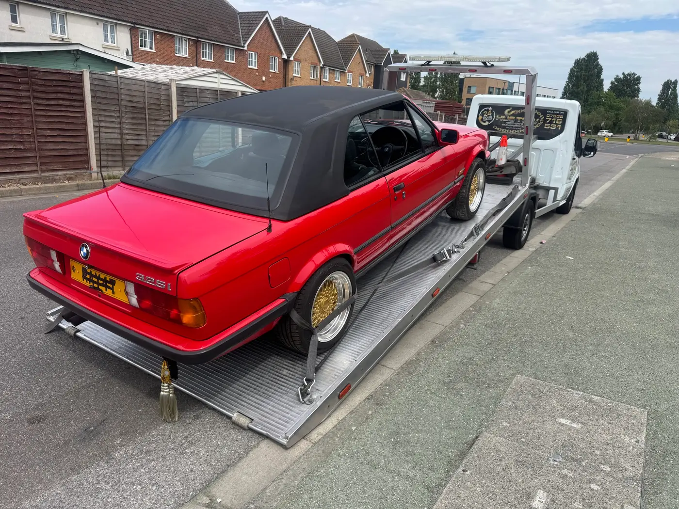 Classic red BMW 325i convertible strapped to a HUS TOW flatbed truck