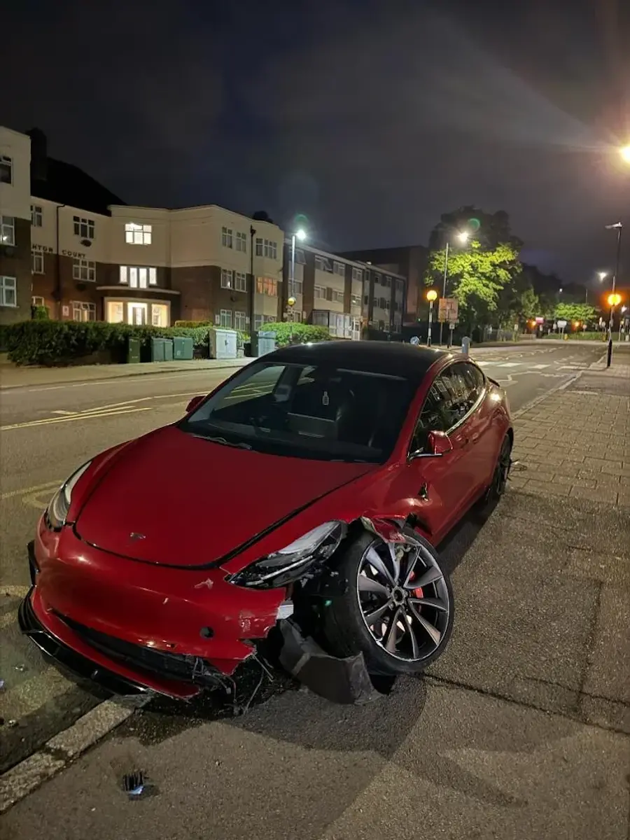 Accident-damaged red Tesla ready for flatbed recovery at night